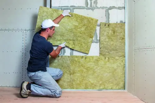 Artisan posant des panneaux de laine minérale sur un mur