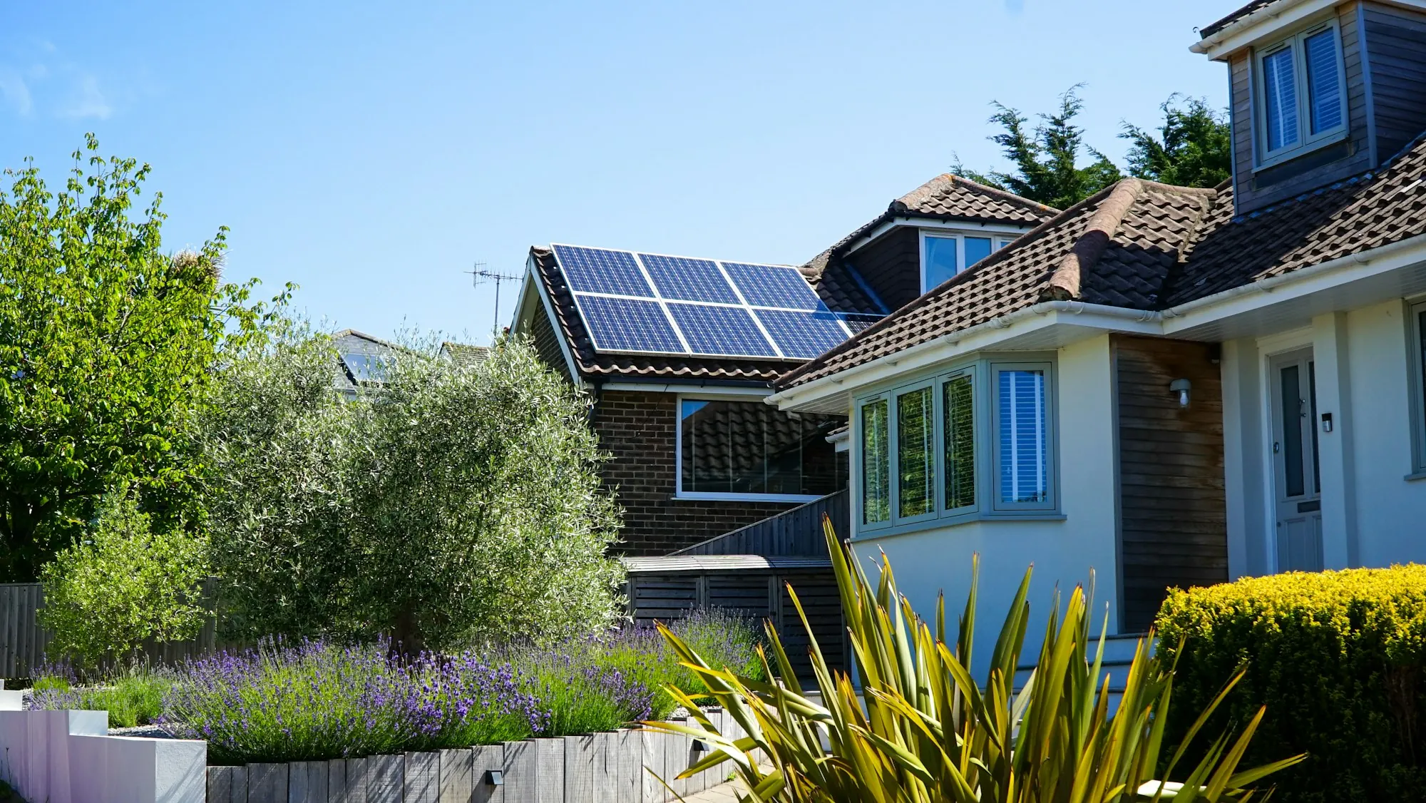 Maison avec panneaux solaires et jardin fleuri au soleil