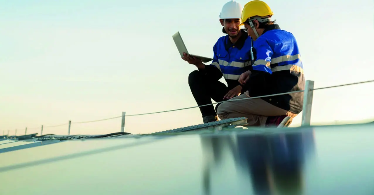 Deux techniciens en casque vérifient une installation solaire